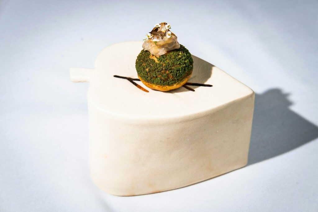 Gourmet dessert with green topping on white plate.