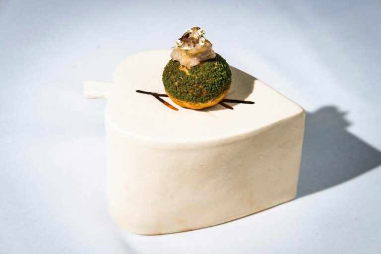 Gourmet dessert with green topping on white plate.